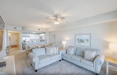 a living room with two couches and a dining room at Calypso 3-1006 by Emerald Coast Retreats in Panama City Beach