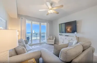 a living room with a couch and a flat screen tv at Calypso 3-1006 by Emerald Coast Retreats in Panama City Beach