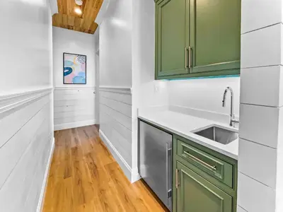 a kitchen with green cabinets and a wooden floor at Summer Wind l Ocean Views, Steps to Beach, Private Pool and Jacuzzi, Golf Cart, Bikes, Ample Parking in Seagrove Beach