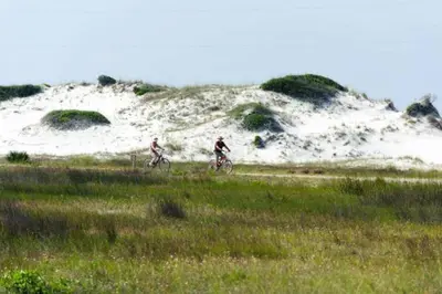 two people riding bikes in a field with a sand hill at Aqua! Under The Sea! - Beach Access! - Pool! in Seacrest