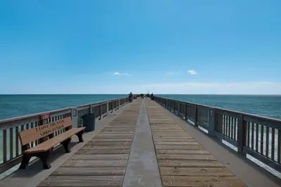 a wooden pier with benches and the ocean at Blue Lagoon (3/2.5) in Panama City Beach