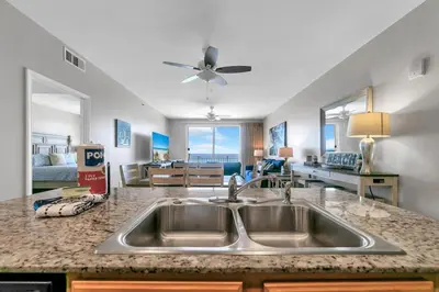 a kitchen with a sink and a living room at Beachfront Condo in Panama City Beach! in Panama City Beach