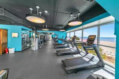 a gym with a row of treadmills and the beach at Beachfront Condo in Panama City Beach! in Panama City Beach