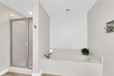 a white bathroom with a tub and a shower at Beachfront Condo in Panama City Beach! in Panama City Beach