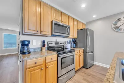 a kitchen with wooden cabinets and stainless steel appliances at Beachfront Condo in Panama City Beach! in Panama City Beach