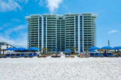 a hotel on the beach with blue chairs and umbrellas at Watercrest 110 in Panama City Beach