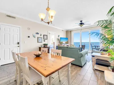 a dining room and living room with a table and chairs at Emerald Isle 1406 by Emerald Coast Retreats in Panama City Beach