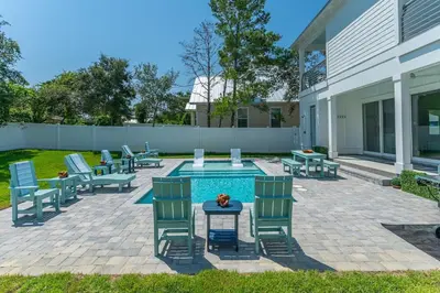 a patio with chairs and a table and a pool at Luxe 8BR with Pool, Golf Cart - 2 Min to Beach in Santa Rosa Beach