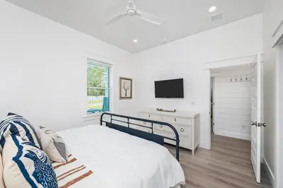 a white bedroom with a bed and a tv at Luxe 8BR with Pool, Golf Cart - 2 Min to Beach in Santa Rosa Beach