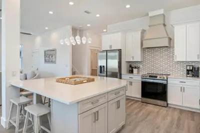 a kitchen with white cabinets and a large island at Ovation- Pool, Beach, Sleeps 21! in Santa Rosa Beach