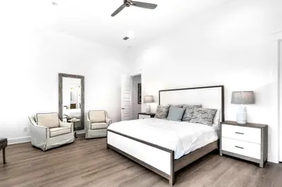 a white bedroom with a bed and a chair at NEW- Horizon! Private Beach - Golf Cart - Pool in Santa Rosa Beach