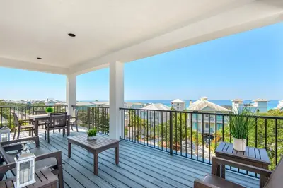 a large deck with tables and chairs on a balcony at NEW- Horizon! Private Beach - Golf Cart - Pool in Santa Rosa Beach