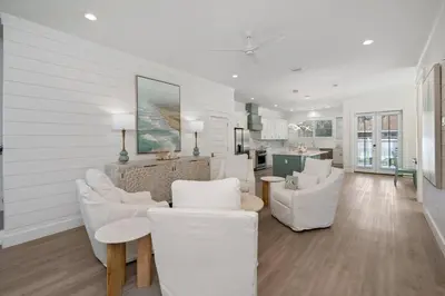 a living room with white furniture and a kitchen at NEW! Symphony! Sleeps 18 - Pool - Golf Cart in Santa Rosa Beach