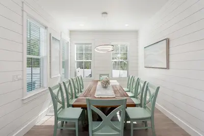 a dining room with a wooden table and green chairs at NEW! Symphony! Sleeps 18 - Pool - Golf Cart in Santa Rosa Beach