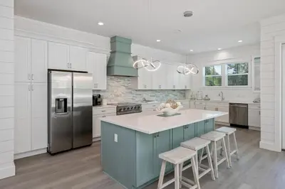 a kitchen with white cabinets and a blue island with stools at NEW! Symphony! Sleeps 18 - Pool - Golf Cart in Santa Rosa Beach