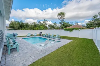 a backyard with a pool and chairs and a fence at NEW! Symphony! Sleeps 18 - Pool - Golf Cart in Santa Rosa Beach
