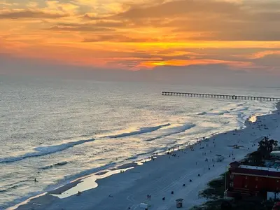 a beach with people and a pier in the ocean at Peaks and Tide - Majestic Beach Resort in Panama City Beach