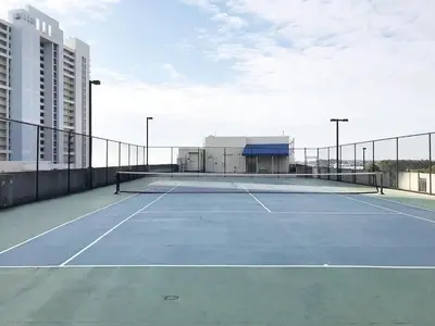 a tennis court in front of a building at Peaks and Tide - Majestic Beach Resort in Panama City Beach