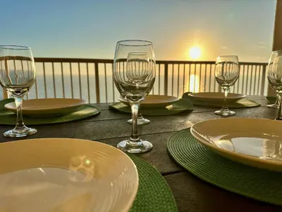 a wooden table with plates and wine glasses on it at Peaks and Tide - Majestic Beach Resort in Panama City Beach