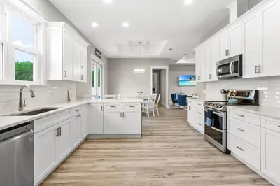 a kitchen with white cabinets and a wooden floor at 4BD3BA Beach House West end PCB in Panama City Beach