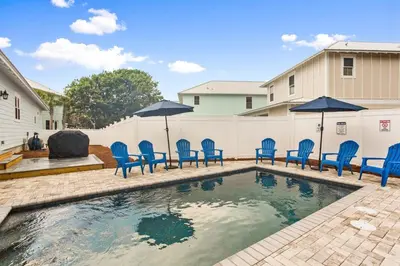 a swimming pool with blue chairs and umbrellas at 4BD3BA Beach House West end PCB in Panama City Beach