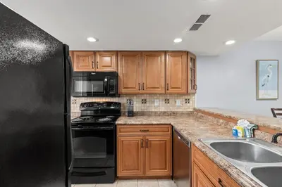 a kitchen with a black refrigerator and a sink at Commodore 0809 in Panama City Beach