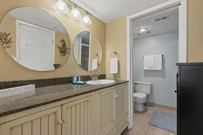 a bathroom with a sink and a mirror and a toilet at Commodore 0809 in Panama City Beach