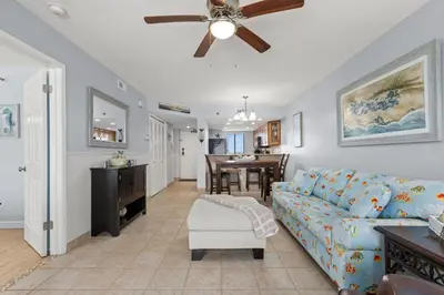 a living room with a blue couch and a ceiling fan at Commodore 0809 in Panama City Beach