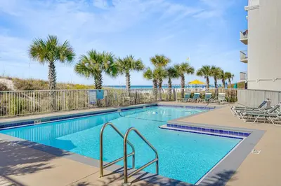 a swimming pool with palm trees and a beach at Prime Beach Access and Gulf-View Balcony! PBC Condo in Panama City Beach