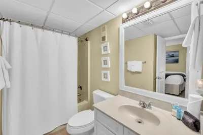 a bathroom with a sink and a toilet and a mirror at Edgewater Resort! 2BR Sleeps 8! 1st Floor Condo! by Dolce Vita Getaways PCB in Panama City Beach