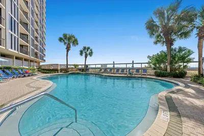 a swimming pool with palm trees and a building at Edgewater Resort! 2BR Sleeps 8! 1st Floor Condo! by Dolce Vita Getaways PCB in Panama City Beach