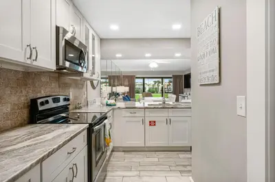 a kitchen with white cabinets and a stove top oven at Mermaid's Den in Panama City Beach