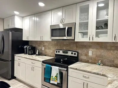 a kitchen with white cabinets and a stove and microwave at Mermaid's Den in Panama City Beach