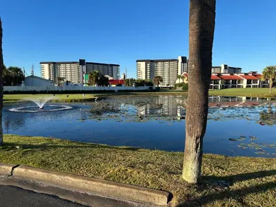 a park with a pond with ducks and buildings at Mermaid's Den in Panama City Beach