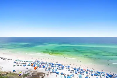 an aerial view of a beach with umbrellas and people at One Seagrove Place 1404 in Santa Rosa Beach