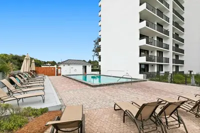 a patio with chairs and a swimming pool at One Seagrove Place 1404 in Santa Rosa Beach