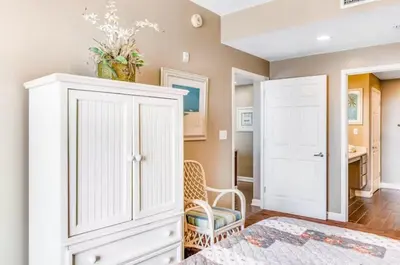 a bedroom with a white cabinet and a chair at Sterling Reef 405 by Emerald Coast Retreats in Panama City Beach