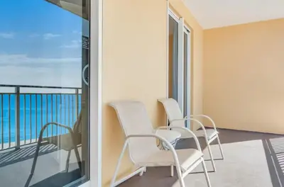 a room with chairs and a balcony with the ocean at Sterling Reef 405 by Emerald Coast Retreats in Panama City Beach