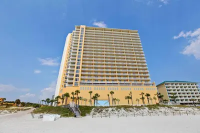 a large yellow building on the beach with palm trees at Sterling Reef 405 by Emerald Coast Retreats in Panama City Beach