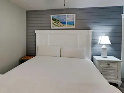 a white bed in a bedroom with a blue wall at Your Paradise Awaits! in Panama City Beach