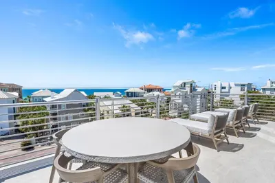 a white table and chairs on a balcony with the ocean at 30A Sunrise and Sunset in Santa Rosa Beach