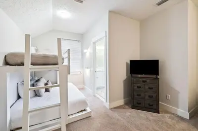 a bedroom with a bunk bed and a flat screen tv at Downward Dog by 30A Escapes in Seacrest