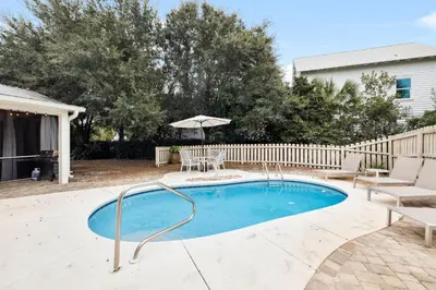 a pool with a table and chairs and an umbrella at Downward Dog by 30A Escapes in Seacrest