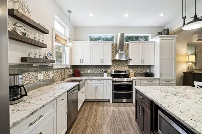 a kitchen with white cabinets and marble counter tops at Downward Dog by 30A Escapes in Seacrest