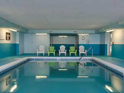 a swimming pool with green chairs in a building at Ocean Reef Starfish in Panama City Beach
