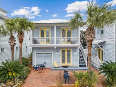 a house with palm trees in front of it at Tram-on-Time Carriage House by 30A Escapes in Rosemary Beach
