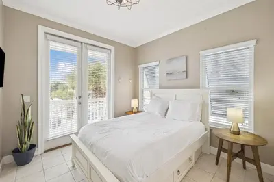 a bedroom with a white bed and two windows at Tram-on-Time Carriage House by 30A Escapes in Rosemary Beach
