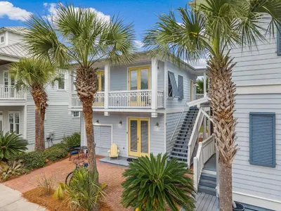 a white house with palm trees in front of it at Tram-on-Time Carriage House by 30A Escapes in Rosemary Beach