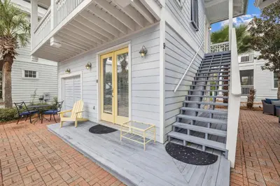 a white house with a staircase on a patio at Tram-on-Time Carriage House by 30A Escapes in Rosemary Beach