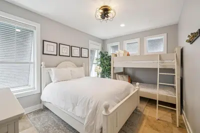 a bedroom with a white bed and bunk beds at Tram-on-Time Main House by 30A Escapes in Rosemary Beach